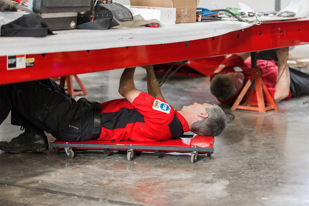 service rep under four post lift installing