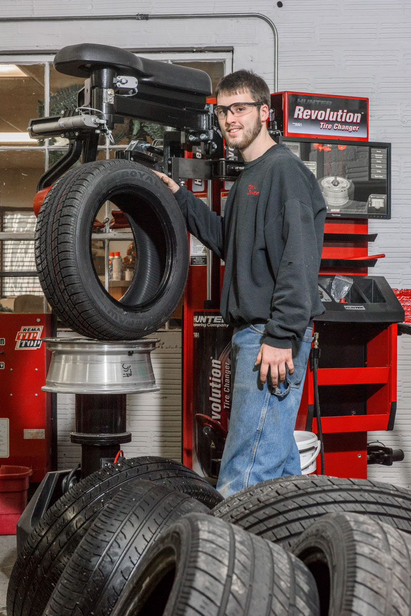 technician smiling with tire and revolution tire changer